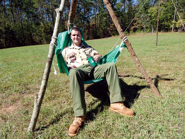 Scout sitting in a homemade camp chair made with tarp and lashings