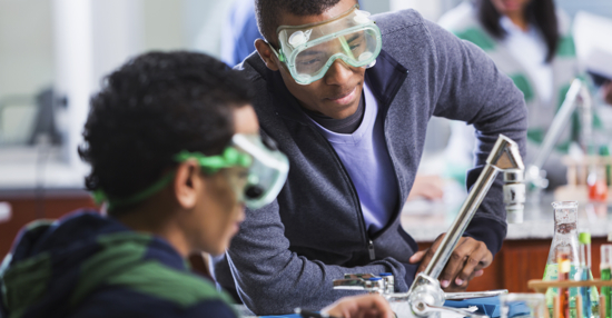 Multi-ethnic group of students in chemistry lab. Focus on African American student (18 years).