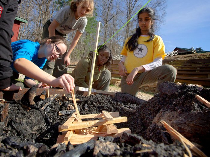 Four Scouts BSA members work on arranging a campfire