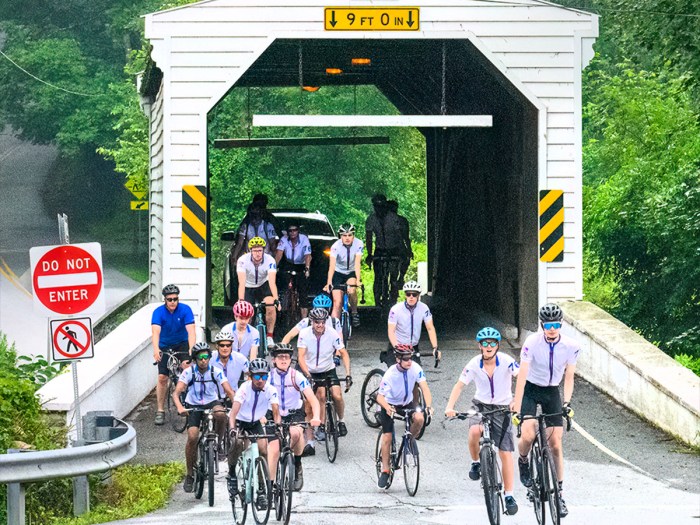 The Scouts cycle through a covered bridge.
