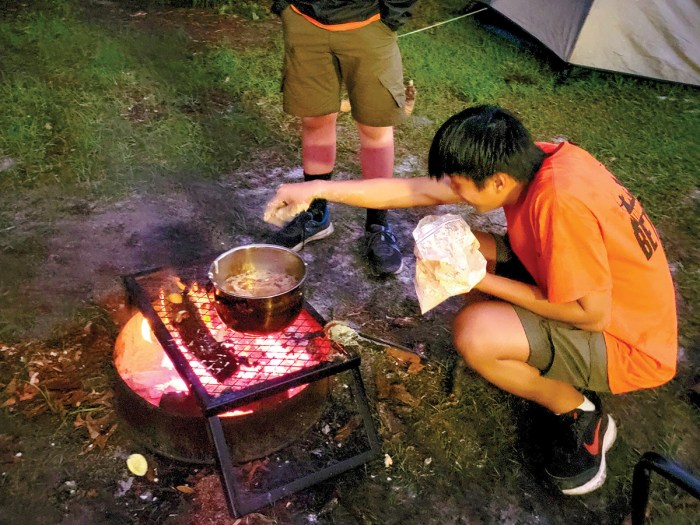Hieu Nguyen fries a fish over an open fire.