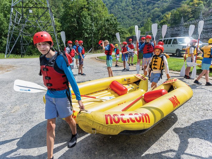 Scouts carry inflatable kayaks to the river