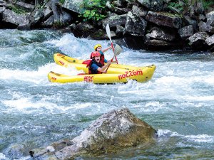 Two Scouts paddle inflatable kayaks through the rapids