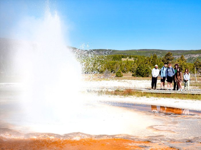 Scouts on boardwalk watching a geyser erupt