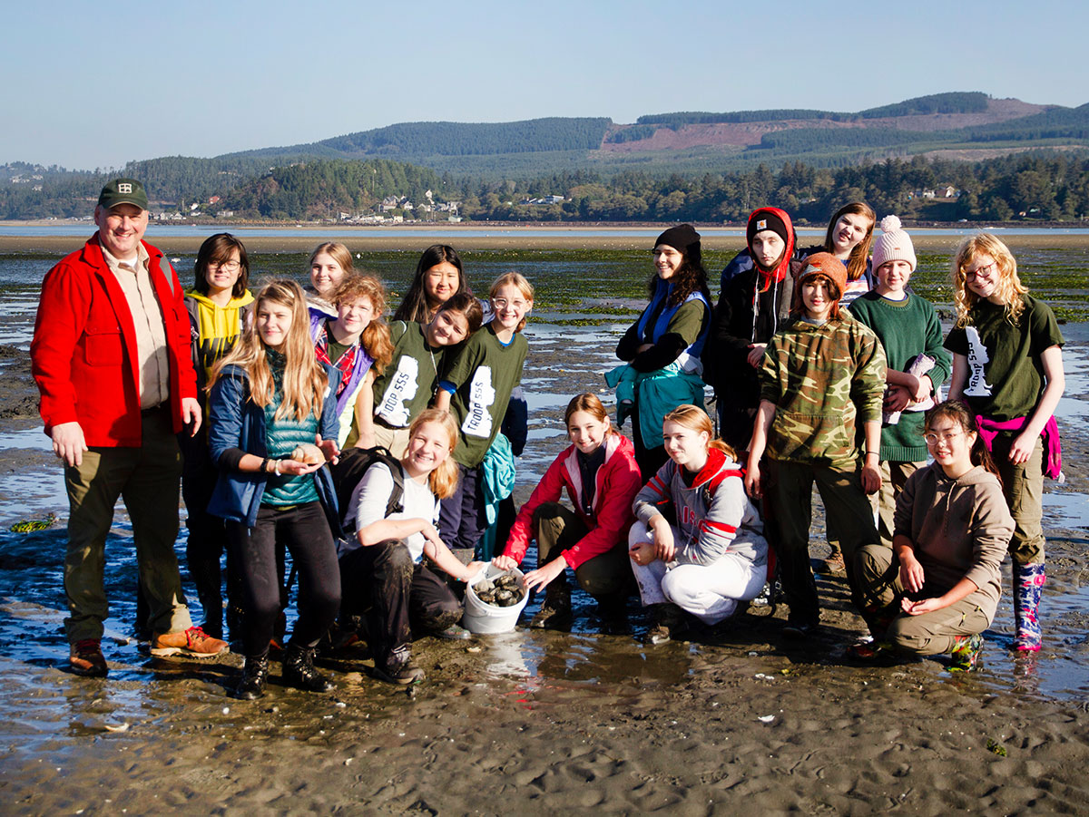 Scout troop posing on a mud flat with clams they found