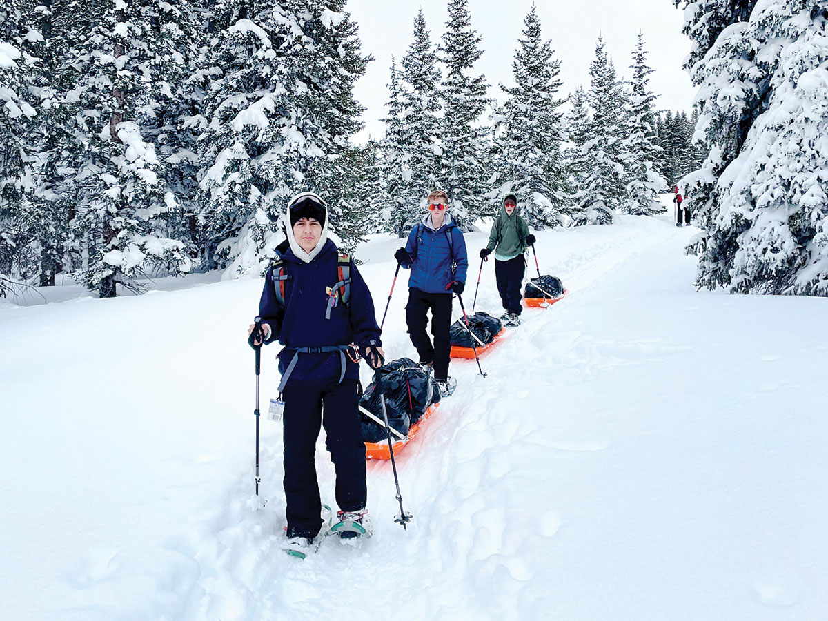 Scouts pull pulk sleds while snowshoeing in Colorado