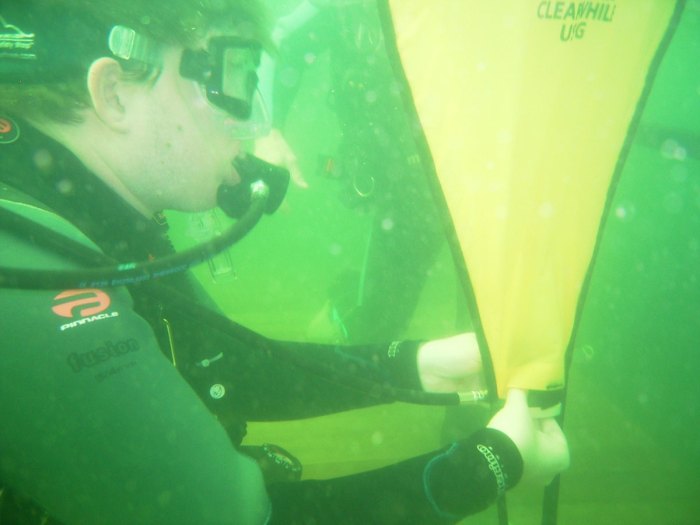 Venturers use inflatable bags to lift trash from lake bottom