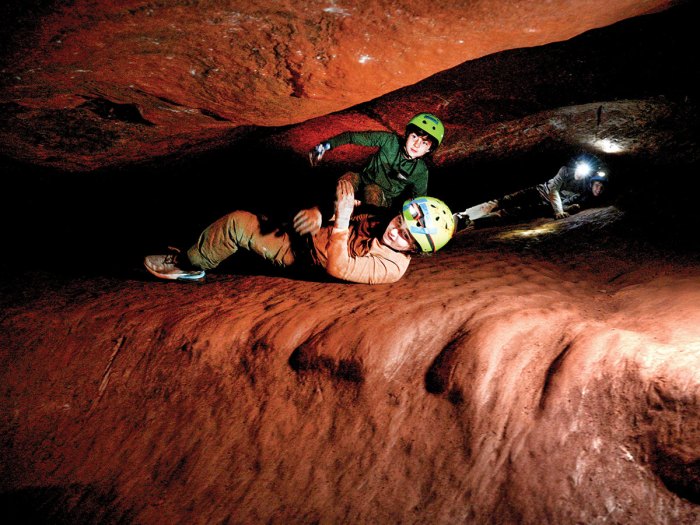 Scouts maneuver through a low part of the cave