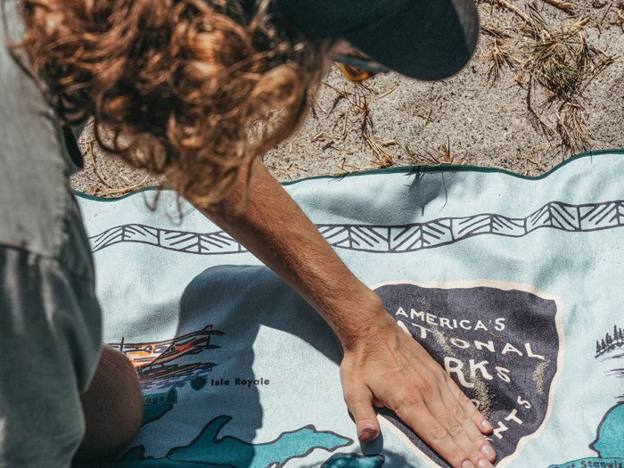 youth spreads out a towel on the beach